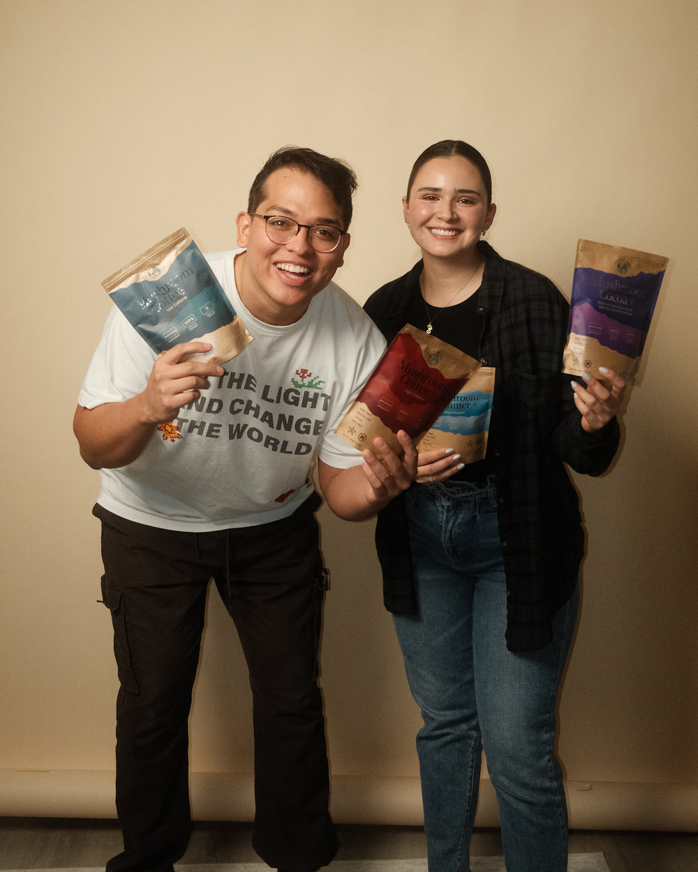 Two people holding books against a beige wall